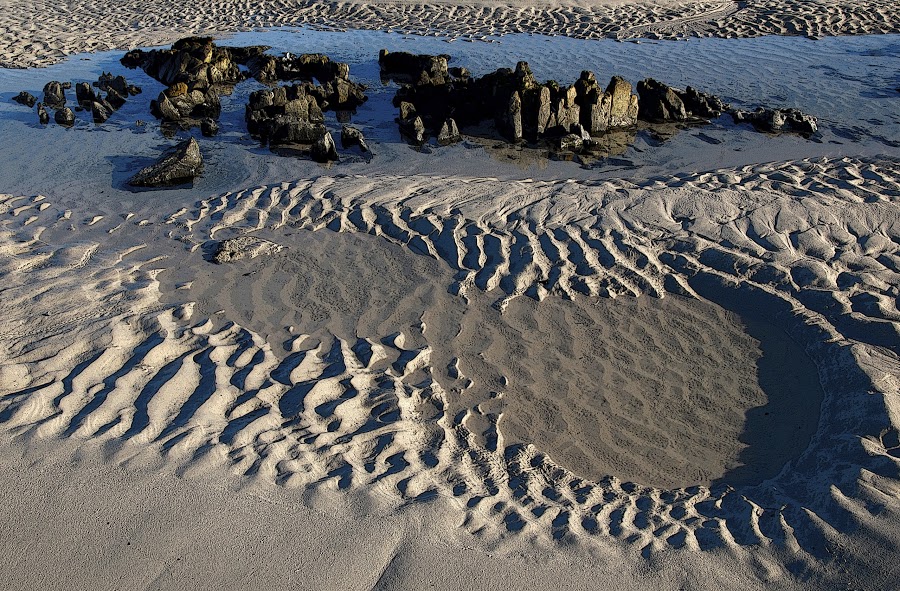 A ridged beach with water on it.